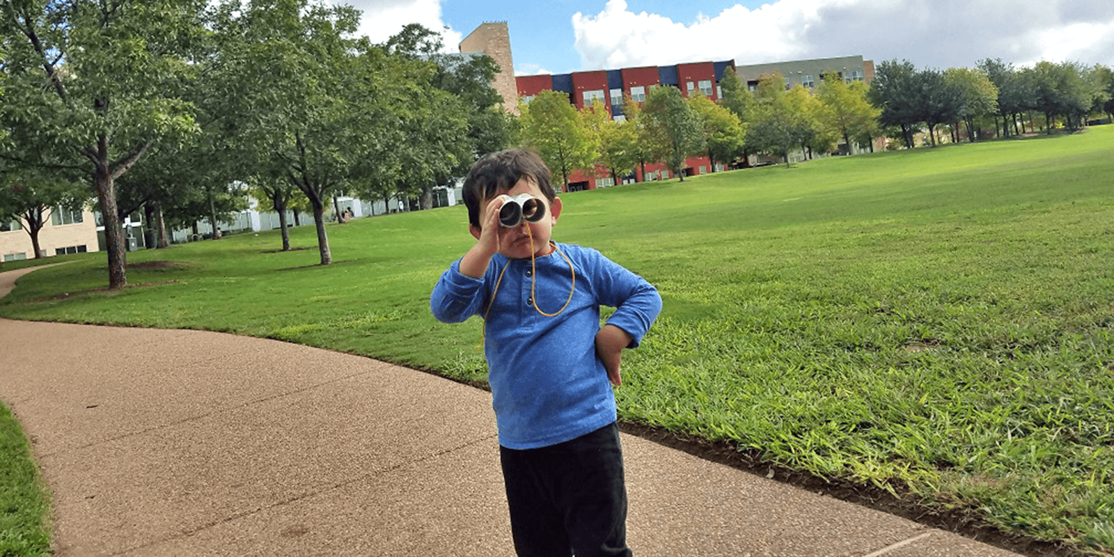 Young boy looking through binoculars at park